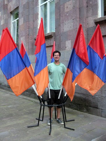 A man stands in the middle of 6 Armenian flags