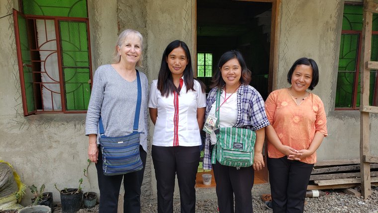 Four people standing in front of building and smiling