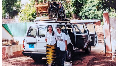 Two female Peace Corps Volunteers stand behind a packed truck.