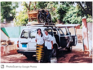 Two female Peace Corps Volunteers stand behind a packed truck.