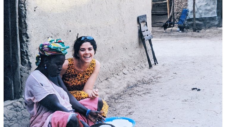 A Peace Corps Volunteer sits next to a woman in Mali.