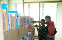 Two boys browse a shelf of library books.
