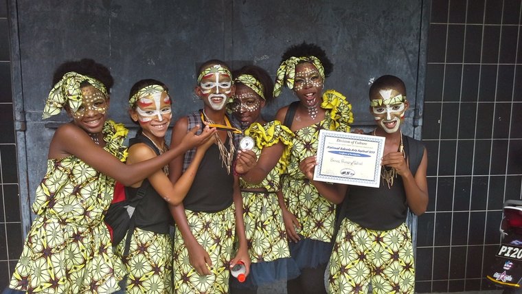 A school dance group shows off their award after a performance.