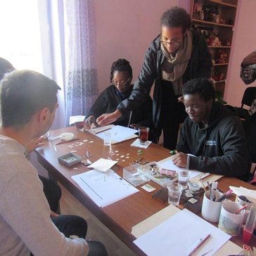 Some out-of-town visitors and Peace Corps Volunteers learn how to make enamel jewelry during a workshop.