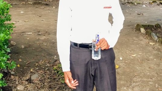 David stands, smiling for the camera. He's holding a water bottle.