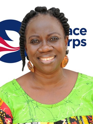 A woman smiles in front of a Peace Corps flag