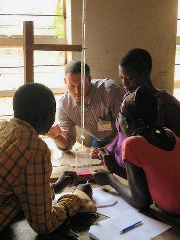 Travis and three students huddle around a table mid-lesson