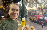 A young woman takes a selfie eating at window countertop.