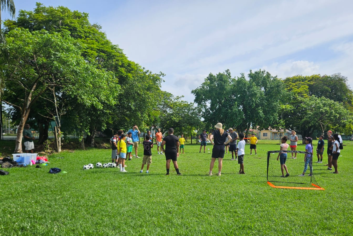 youth practicing sports on the field with volunteers