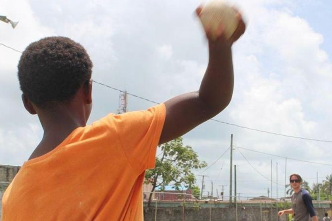 boy throwing baseball to volunteer