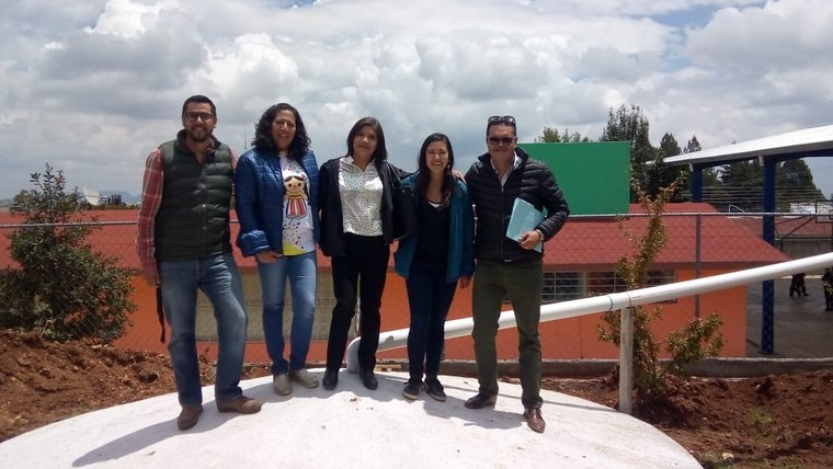 Volunteer Cassidy Pearson and collaborators pose on top of the 50,000 liter capacity water cistern.
