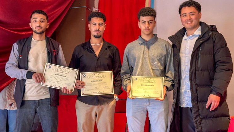 Four young men hold certificates of achievement.