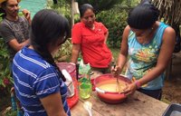 A woman uses in a whisk in bowl while baking outside