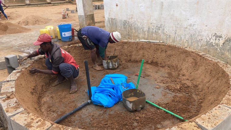 Two men constructing a water tank foundation
