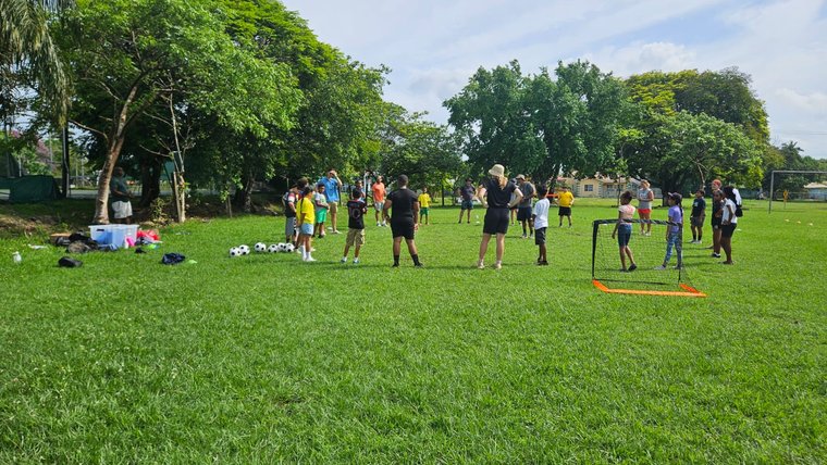 youth practicing sports on the field with volunteers