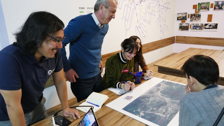 Volunteer and counterparts around a table of students working on a mapping project.