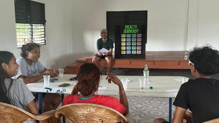 Joseph leads a game of “Health Jeopardy” with youth in a local village.