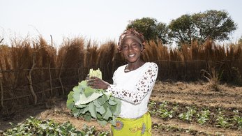 Host Country National Posing with Garden Vegetables in Zambia