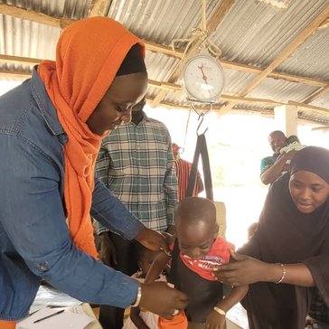 Volunteer Aji Mary assist the village post in her community by weighing babies on clinic days