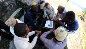 Aspiring beekeepers in Comoros ask lots of questions to PCRV Ellen Geisler as they prepare to open a beehive for the first ti