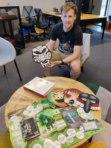 A man sits to play a board game with animal masks