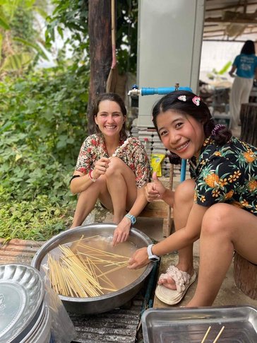 Kayla and her friend Namtan prepare squid to be barbecued and sold at a Songkran (Thai new year) festival.