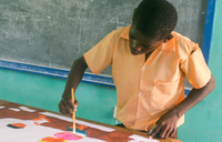 A deaf student works on his poster for an HIV/AIDS prevention art contest