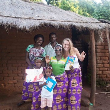 Health Volunteer Emma poses with her Malawain family--all wearing purple chitenje skirts.