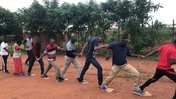 A group of teachers in Malawi hold hands in a line as they do a team building activity outside
