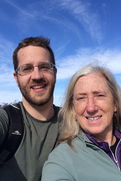 A young white male and his mother take a selfie outside.