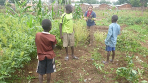 Peace Corps Volunteer Genevieve James teaches students how to collect seeds to plant next year.