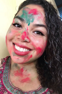 Headshot of smiling girl with face covered in colored powder