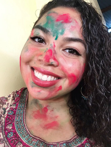 Headshot of smiling girl with face covered in colored powder