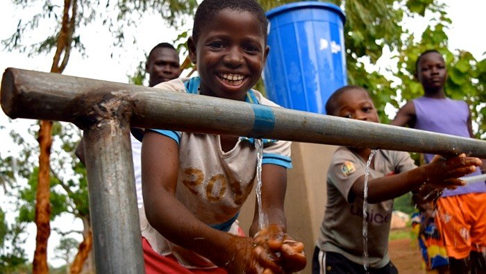 Young students happily use a handwashing station installed at their middle school.