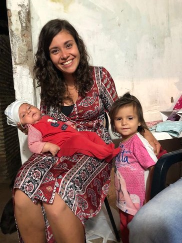 A PCV in Paraguay poses with the babies of her host family.