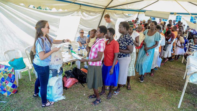 Volunteer Anna hands out bed nets to a line of Malawians.