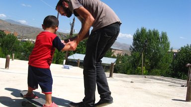 Volunteer Jonathan teaching a little boy how to skateboard in Armenia