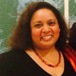Female Country Director wearing a black colored top and a red necklace