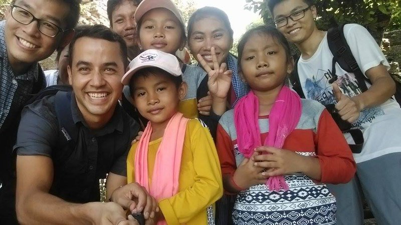 Latinx Volunteer poses with his Cambodian host family.