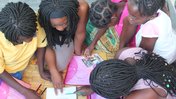 Little girls read in Malawi with the help of their teacher