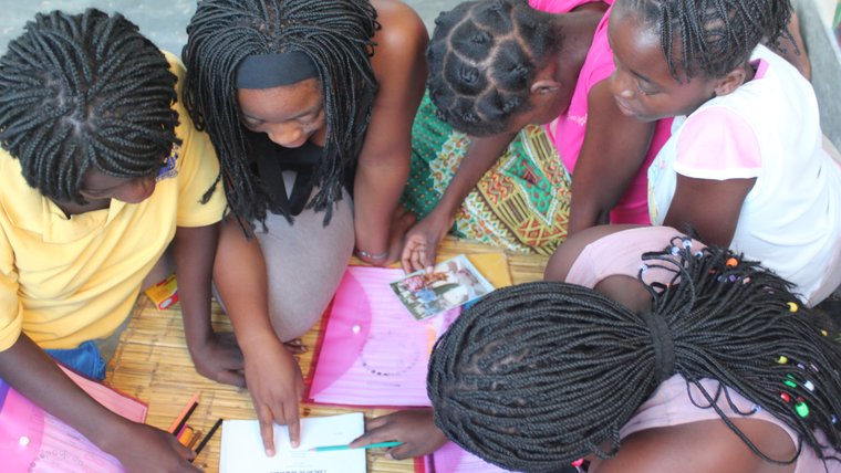 Little girls read in Malawi with the help of their teacher