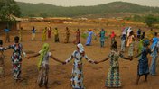 Women hold hands in a circle in Guinea.