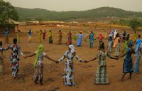 Women hold hands in a circle in Guinea.