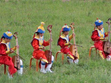 Four Mongolian children in traditional dress playi the morin khuur.