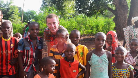 Robbie Lehman standing with children in his community.