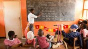 A teacher in Malawi teaches young children in a small classroom