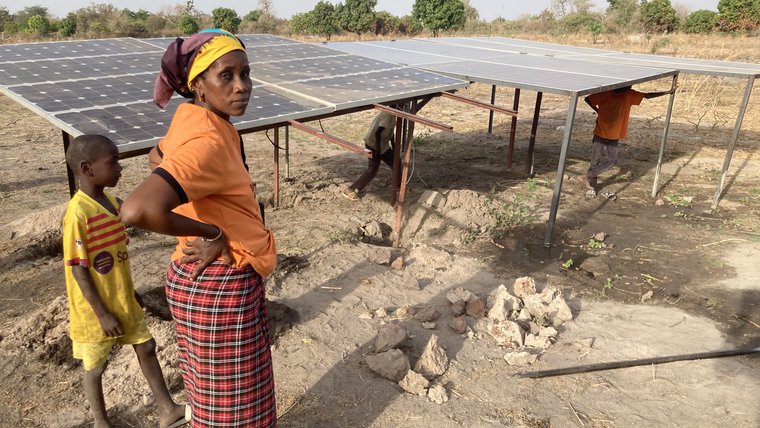 Host Mother standing next to newly installed solar panels in the community Garden.
