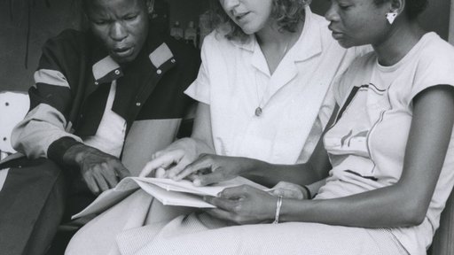 A Volunteer sits with two of her students in Botswana.