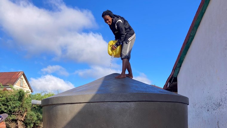A young woman stands on top of a water tank