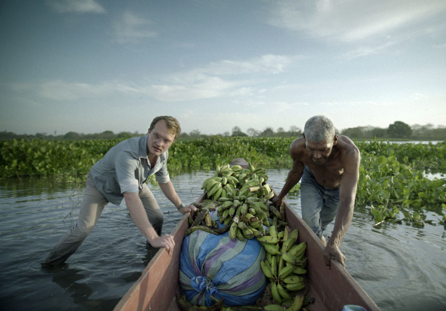Two people guiding a canoe filled with bananas
